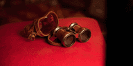 old fashioned cinema viewing binoculars on a red velvet seat